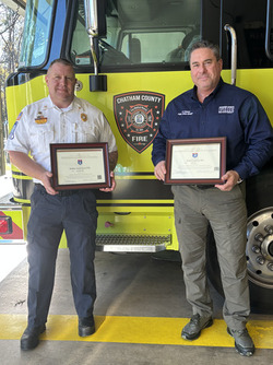 Two CCFD personnel holding certificates in front of a fire truck