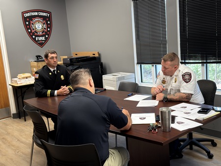 Three fire service personnel perform promotion interview with candidate