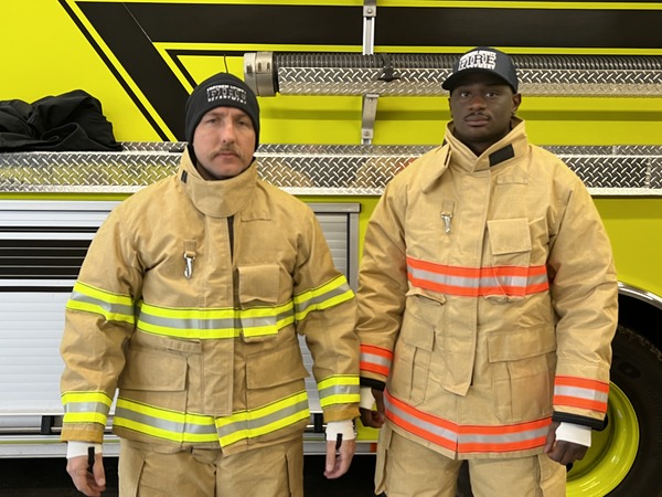 Two CCFD firefighters in new turnout gear in front of a fire truck