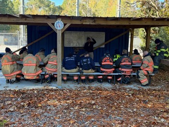 Multiple fire department personnel sitting in front of a white board with an instructor