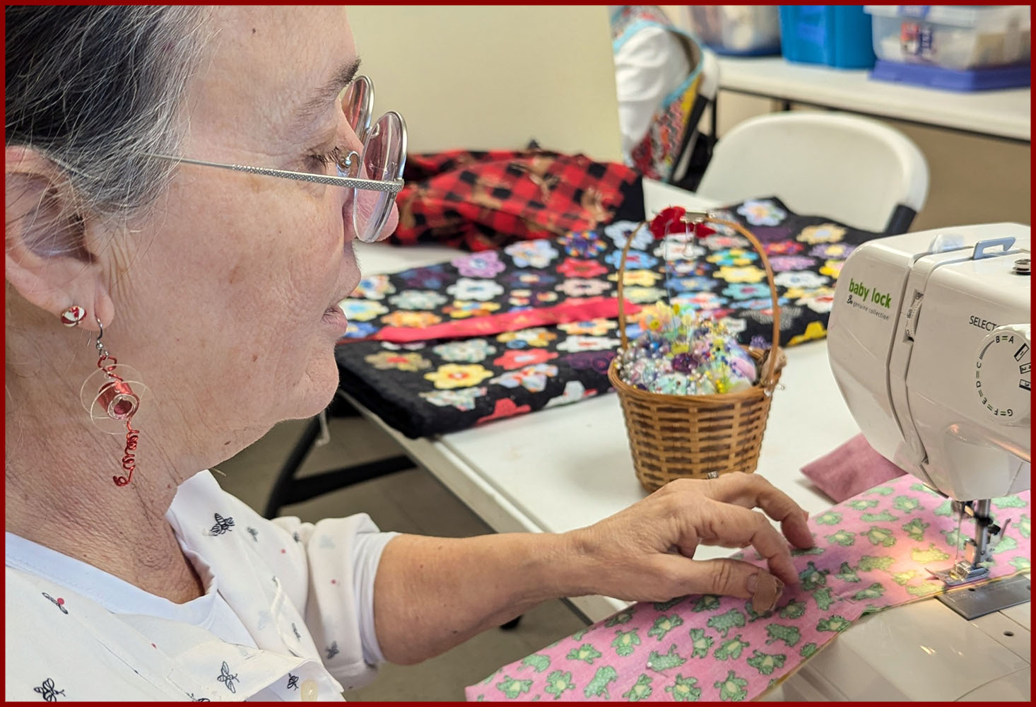 woman with thread and bobbin earring at sewing machine making bright colored pillowcase