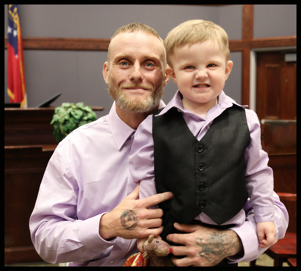 Anchor Court graduate Joshua Dailey smiles with his son after graduation