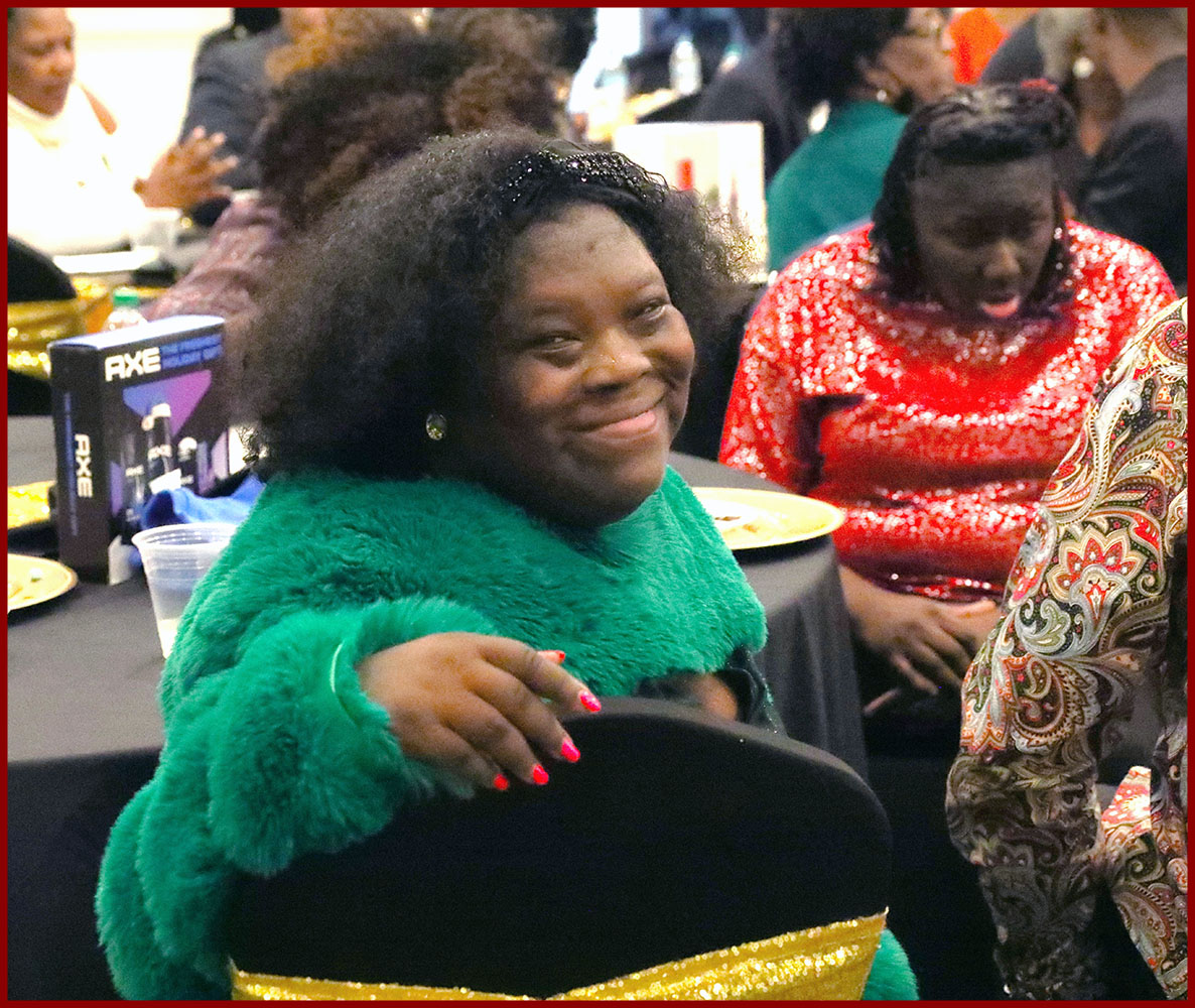 young woman in holiday attire smiles during dinner at a holiday ball