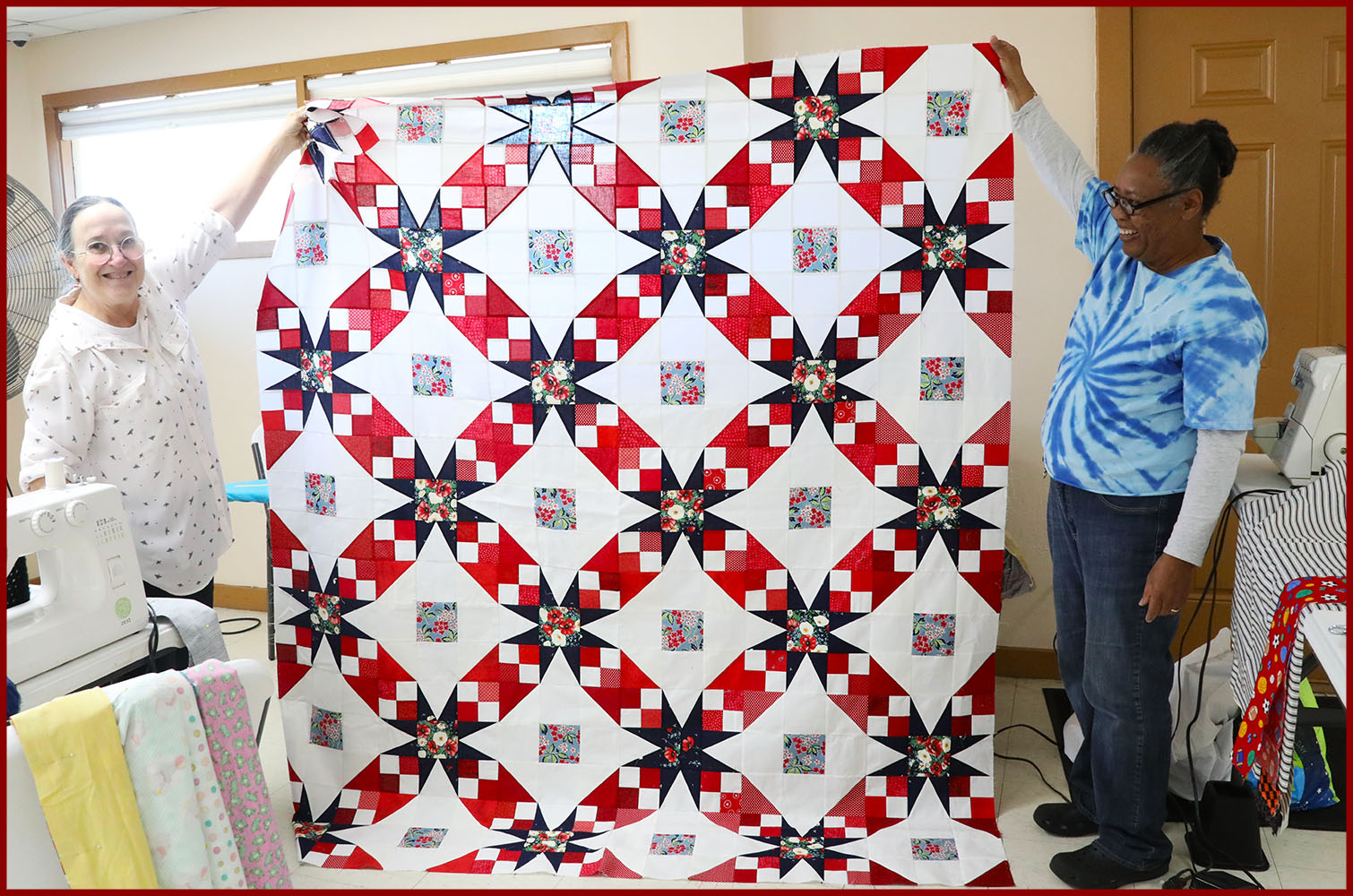 quiltmakers hold up red, white, and blue Quilt of Valor