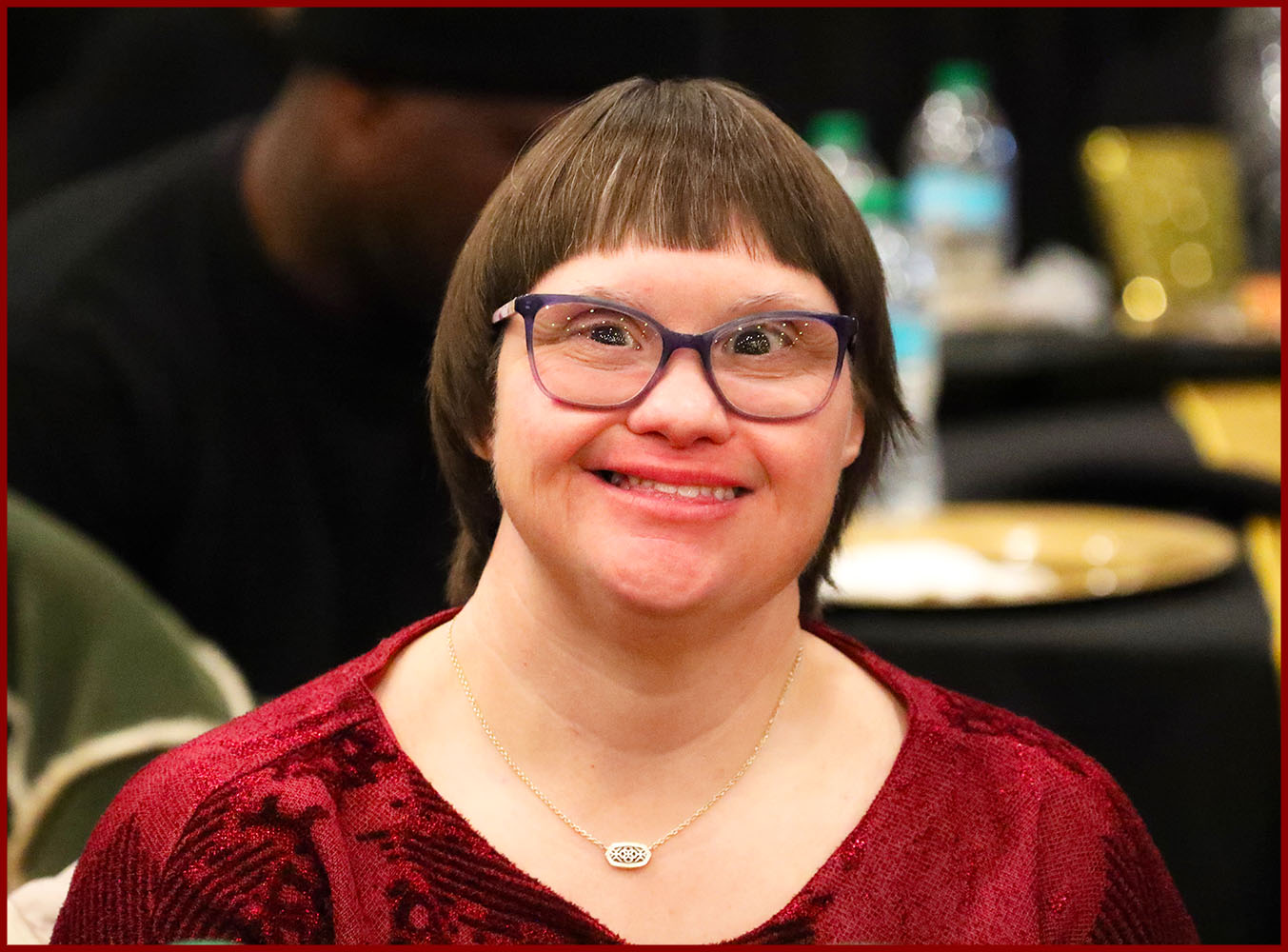 Young woman with downs syndrome smiles with holiday lights reflected in her eyes