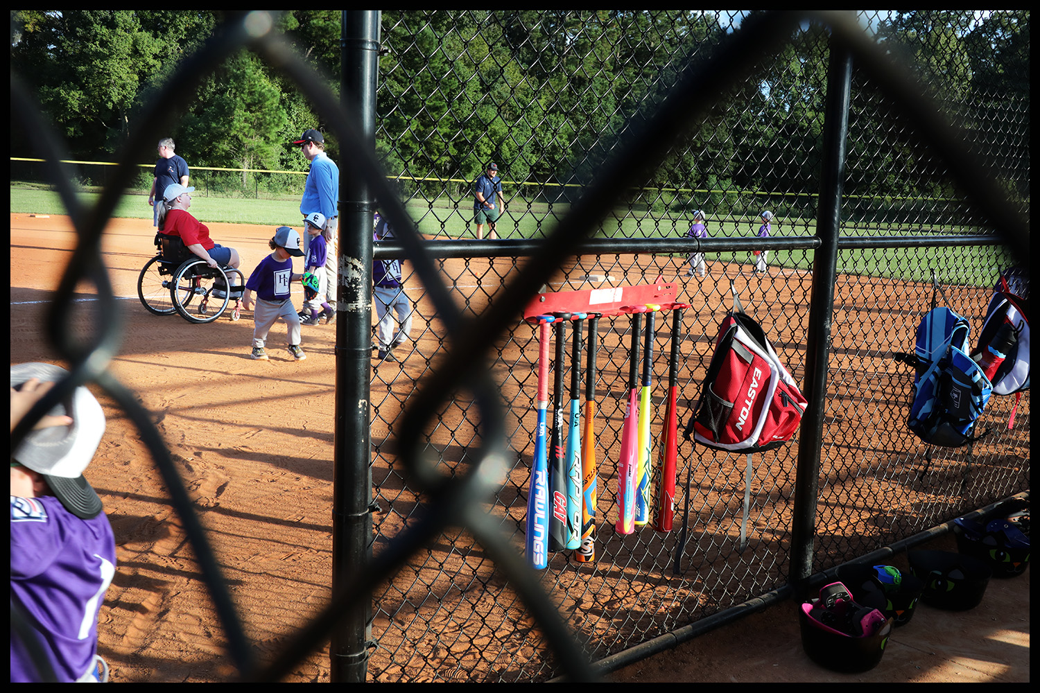 Little league coaches, one in a wheelchair, on the field with players